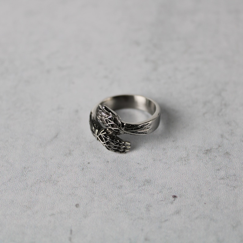 May include: A silver ring with two hands clasped together, forming a circle.