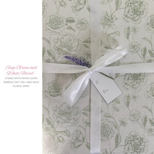 Pode incluir: Um presente embrulhado em papel floral verde s&aacute;lvia e branco, amarrado com uma fita de cetim branca. Uma pequena etiqueta est&aacute; anexada e um raminho floral falso adiciona um toque decorativo. O papel de embrulho apresenta um padr&atilde;o floral repetido.