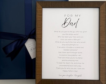 May include: A dark wood frame containing a white print with the text FOR MY Dad followed by a poem about a father, signed Love your daughter, Marybeth. Beside the frame is a dark blue gift box wrapped with a matching navy blue satin ribbon.