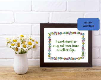 May include: A dark brown picture frame containing a white print with the green text I work hard so my cat can have a better life, surrounded by a colorful border of small paw prints in shades of red, blue, yellow, and purple.