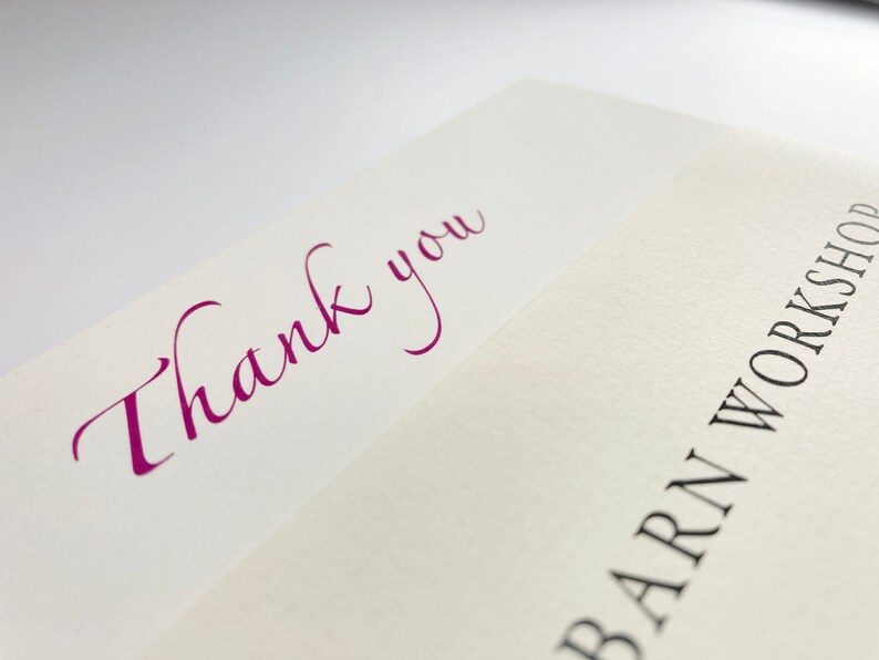 May include: A white card with the words "Thank you" written in purple cursive script. The bottom of the card has the words "Barn Workshop" printed in black.