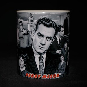 May include: A black and white ceramic mug featuring a collage of images of a man in a suit, with the text "PERRY MASON" in red. The mug has a glossy finish and a cylindrical shape.
