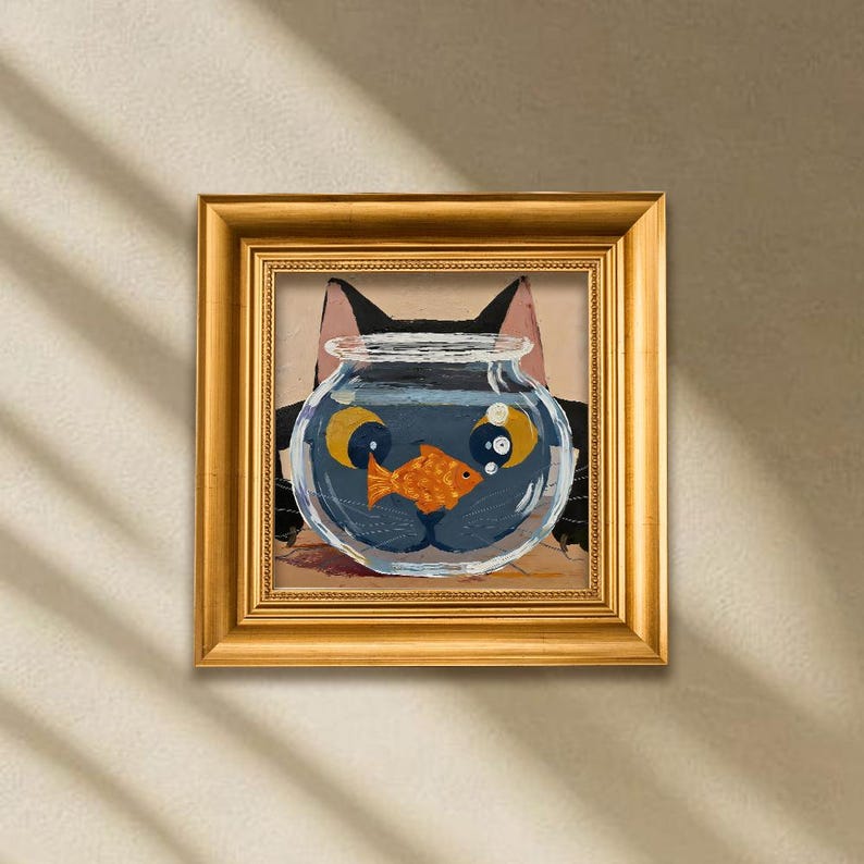 May include: A framed painting features a black cat with a fishbowl for a face. The fishbowl contains an orange goldfish. The painting is in a gold frame and is displayed on a beige wall.
