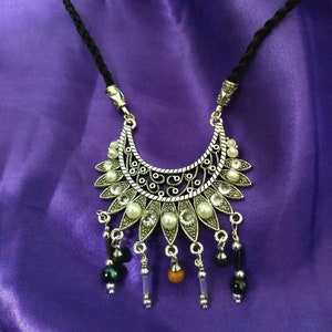 Pearl beading and zirconium stones set in an antique silver pendant piece. Two by two inches on a black satin, braided, adjustable cord.