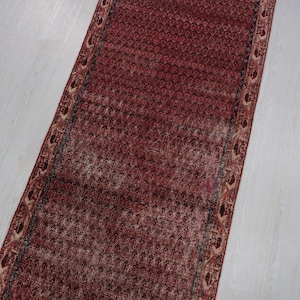 May include: A red runner rug with a patterned border. The rug has a traditional design with intricate details.