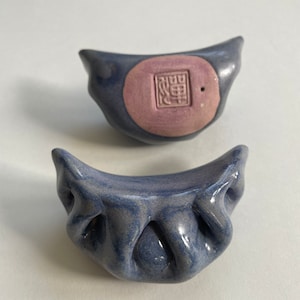 Peut inclure: Deux boulettes en c&eacute;ramique bleues et violettes avec un motif en relief. La boulette du haut a un cercle rose avec un caract&egrave;re chinois au centre.