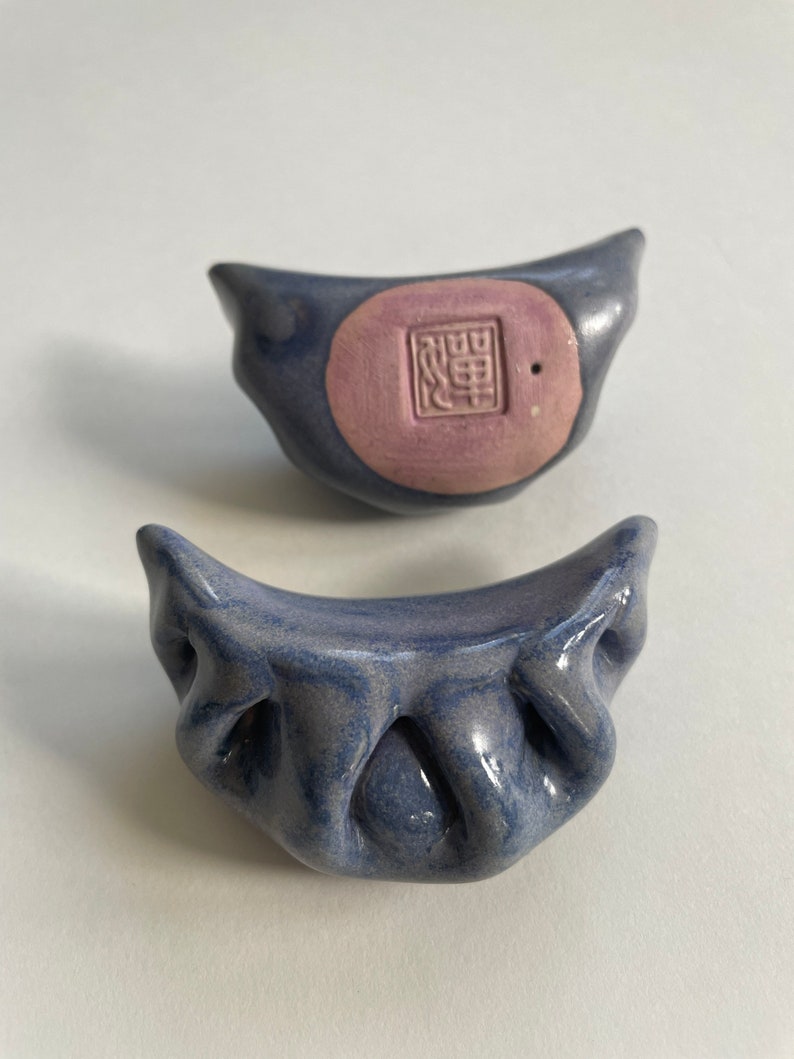 Peut inclure: Deux boulettes en c&eacute;ramique bleues et violettes avec un motif en relief. La boulette du haut a un cercle rose avec un caract&egrave;re chinois au centre.