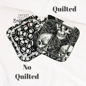 May include: Two square pot holders with skull and bone patterns. One is black and white with skulls and bones, the other is black and grey with skulls and roses. The pot holders have a grey border.