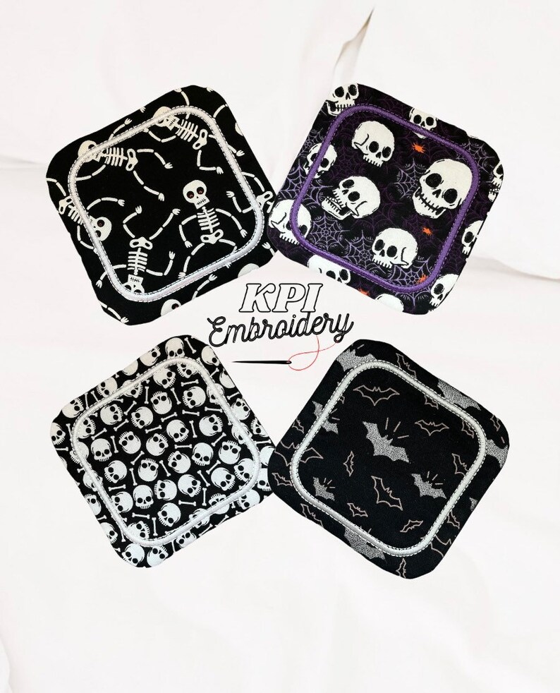 May include: Four square Halloween-themed coasters. Each coaster features a different black and white design: skeletons, skulls, skull pattern, and bats. The coasters have a white border and are from KPI Embroidery.
