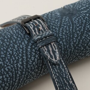 May include: A blue leather watch strap with white stitching and a black buckle.
