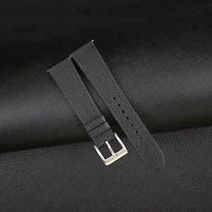 May include: Black leather watch strap with a silver buckle.