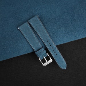 May include: A teal blue suede watch strap with a silver buckle.
