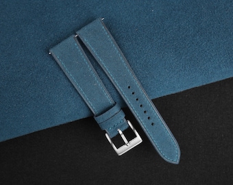 Könnte beinhalten: Ein blaues Wildleder-Armband für eine Uhr mit einer silbernen Schließe.