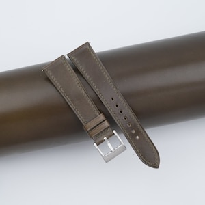 May include: Two brown leather watch straps with stitching. One strap is wider than the other and has a buckle.
