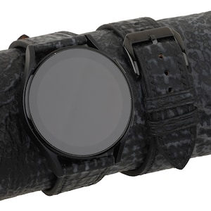 May include: A black smartwatch with a black leather band. The band has a textured pattern.