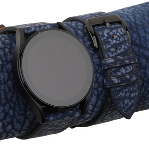 May include: A black smartwatch with a blue leather strap. The strap has a textured pattern.