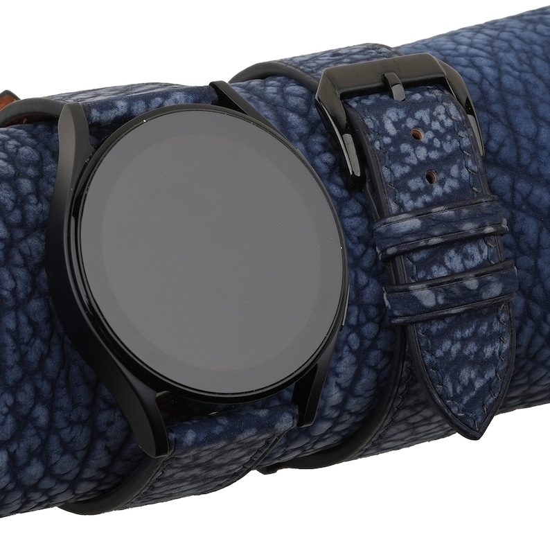 May include: A black smartwatch with a blue leather strap. The strap has a textured pattern.