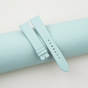 May include: Two light blue leather watch straps, one is rolled up and the other is laid flat.