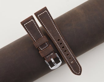 May include: Two brown leather watch straps with white stitching. The straps have a silver buckle with the word "PANERAI" engraved on it.