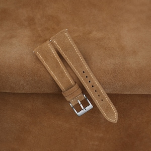 May include: Two brown suede watch straps with white stitching and silver buckles.