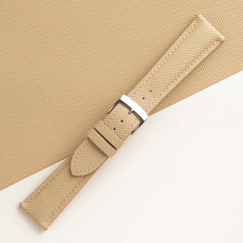 Puede incluir: Correa de reloj de color beige con superficie texturizada y hebilla plateada. La correa tiene un dise&ntilde;o cl&aacute;sico con m&uacute;ltiples orificios de ajuste. La correa del reloj est&aacute; hecha de un material duradero y es adecuada para varios estilos de reloj.