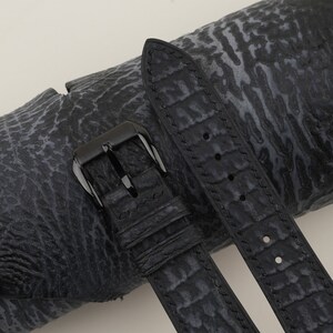 May include: Black leather watch strap with a black buckle. The strap has a textured, alligator-like pattern.