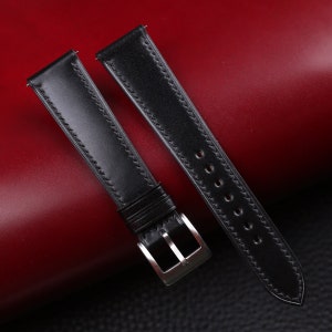 May include: Two black leather watch straps with stitching detail. One strap has a silver buckle.
