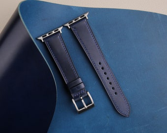 May include: Two dark blue leather watch bands with silver hardware. The bands are laid out on a blue leather surface.