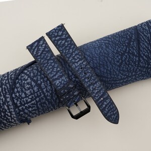 May include: Two blue watch straps with a textured pattern. The straps are made of leather and have black stitching. One strap has a black buckle.