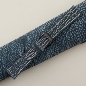 May include: A blue and white striped leather watch strap with a black buckle.