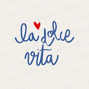 May include: A digital print with the Italian phrase "la dolce vita" in blue script. A small red heart is above the word "dolce". The phrase is set against a cream background.
