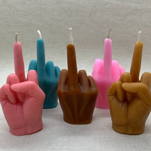 K&ouml;nnte beinhalten: F&uuml;nf handf&ouml;rmige Kerzen, jede in einer anderen Farbe: rosa, blau, braun und zwei weitere rosa Kerzen. Die Kerzen sind in Form eines Mittelfingers geformt.