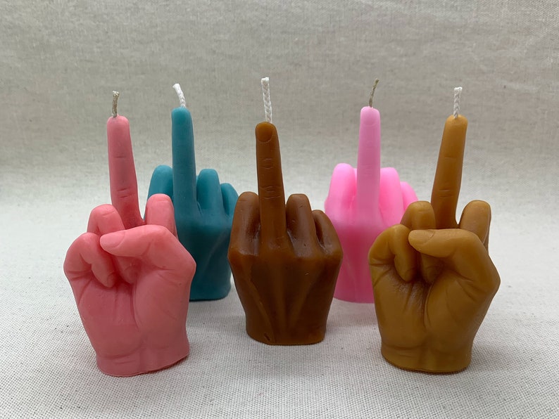 K&ouml;nnte beinhalten: F&uuml;nf handf&ouml;rmige Kerzen, jede in einer anderen Farbe: rosa, blau, braun und zwei weitere rosa Kerzen. Die Kerzen sind in Form eines Mittelfingers geformt.