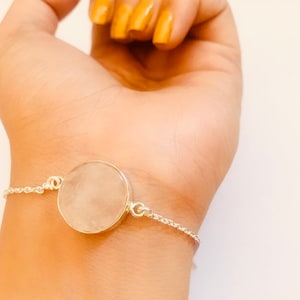 May include: A silver chain bracelet with a large, round, clear quartz stone pendant.