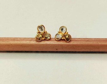 May include: A pair of gold earrings with three clear stones each, set in a clover shape.