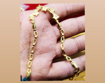 Pode incluir: Um bracelete de corrente de ouro com um design delicado que apresenta pequenos pingentes em forma de estrela. A corrente é feita de elos ovais.