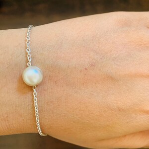 Puede incluir: Un brazalete de cadena de plata con un solo dije de perla blanca.