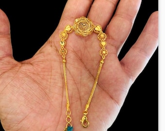 May include: A gold bracelet with a delicate chain and a floral design. The bracelet features a round centerpiece with a floral pattern and heart-shaped accents.