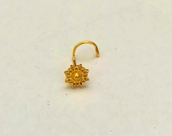 May include: A gold nose ring with a decorative flower design.