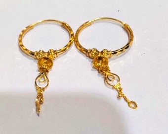 May include: A pair of gold hoop earrings with a dangling charm. The hoops are textured and the charms are intricate.