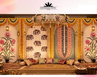 May include: A decorative event backdrop featuring a central panel with an elephant pattern, flanked by panels with large pink floral illustrations. The setup includes a circular hanging canopy, marigold garlands, and a low platform with cushions.