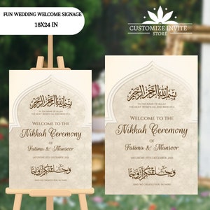 May include: A white welcome sign with a brown border and Arabic calligraphy. The sign reads "Welcome to the Nikkah Ceremony of Fatima & Mansoor, Saturday, 15th December, 2021, and we created you in pairs".