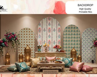 May include: A decorative event backdrop featuring four arched panels with intricate floral and geometric patterns in teal, pink, and gold. The display includes gold lanterns, a carved wooden table, and silk pillows. Text reads BACKDROP.