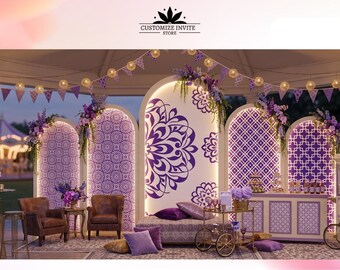 May include: A purple and white event backdrop featuring five arched panels with intricate mandala and geometric patterns, illuminated by string lights and purple bunting. The setup includes two brown armchairs, a low sofa, and a serving cart.