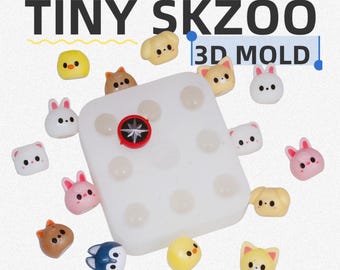 Może przedstawiać: Biała silikonowa forma z wieloma wgłębieniami, otoczona małymi, kolorowymi elementami z żywicy w kształcie zwierząt. Forma ma czerwono-czarny emblemat pośrodku. Tekst "TINY SKZOO 3D MOLD" jest wyświetlany u góry.