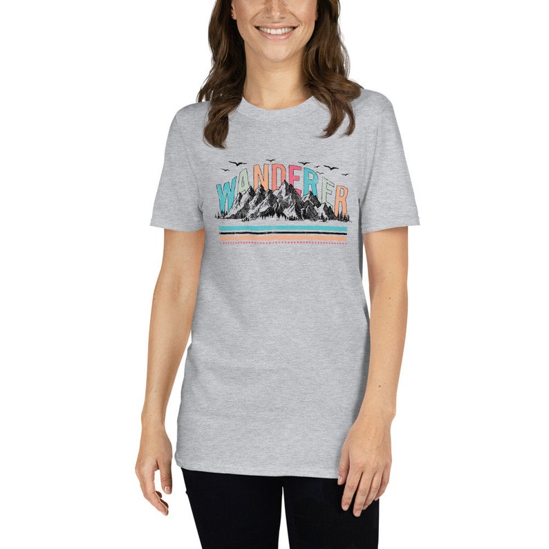 May include: A heather grey t-shirt with a graphic of a mountain range and the word "WANDERER" in colorful letters.