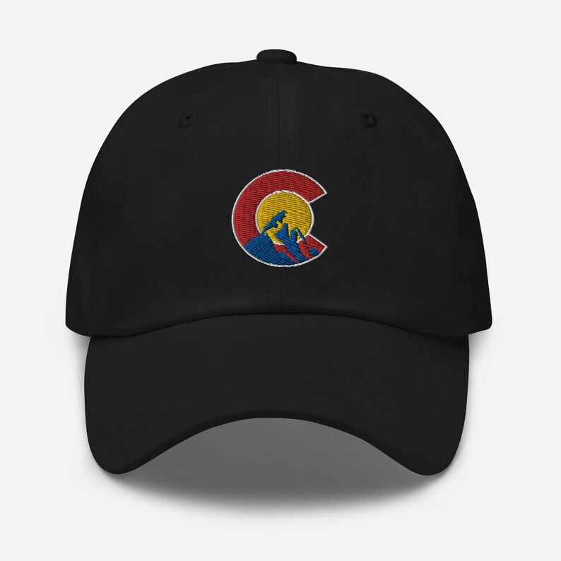 Puede incluir: Gorra de b&eacute;isbol negra con un contorno bordado del estado de Colorado que presenta un sol amarillo y monta&ntilde;as azules.
