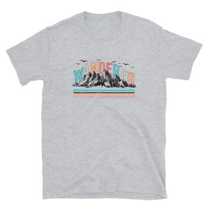 May include: A grey short-sleeved t-shirt with a graphic of mountains and the word "WANDERER" in rainbow colors.