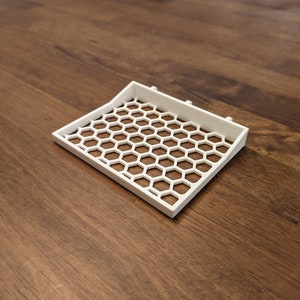 May include: White plastic tray with a honeycomb pattern. The tray is slightly curved and has a raised edge.