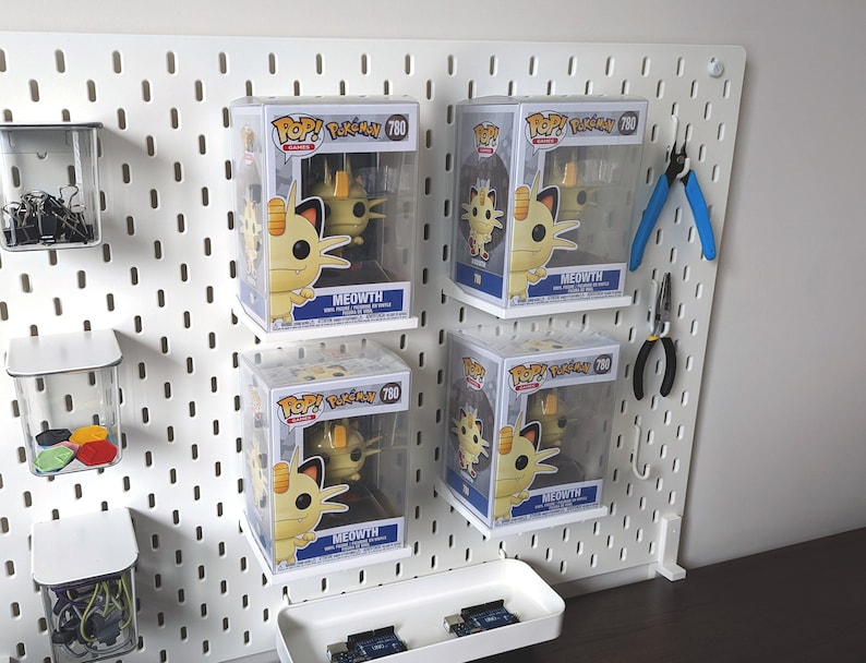 May include: Four white boxes with clear plastic fronts display four identical yellow and white Pokemon figures. The boxes are labeled "POP! Pokemon 780" and "MEOWTH".